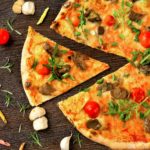 pizza with tomato and green leaves on white ceramic plate
